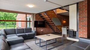 A modern living room with a sectional sofa, a coffee table, and a fireplace. - Well Furnished Home for Groups with Fireplace near Water (Gasselternijveen)