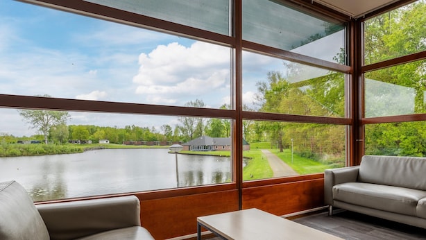 A room with large windows, a sofa, and a table. - Well Furnished Home for Groups with Fireplace near Water (Gasselternijveen)