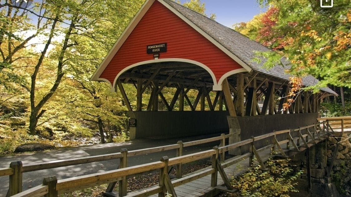 Un puente cubierto con techo rojo y vigas de madera, identificado como "PEMIGWASSER RIVER".