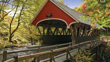 Un puente cubierto con techo rojo y vigas de madera, identificado como "PEMIGWASSER RIVER".