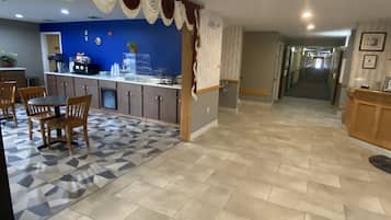 Una cocina amplia con una pared de acento azul, un comedor con sillas de madera y un pasillo que conduce a otras habitaciones.