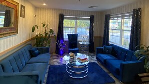 A modern living room with a blue sofa, a glass coffee table, and a patterned floor.