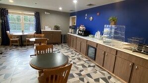 A dining area with a patterned floor, wooden chairs, a round table, and a counter with kitchen appliances.