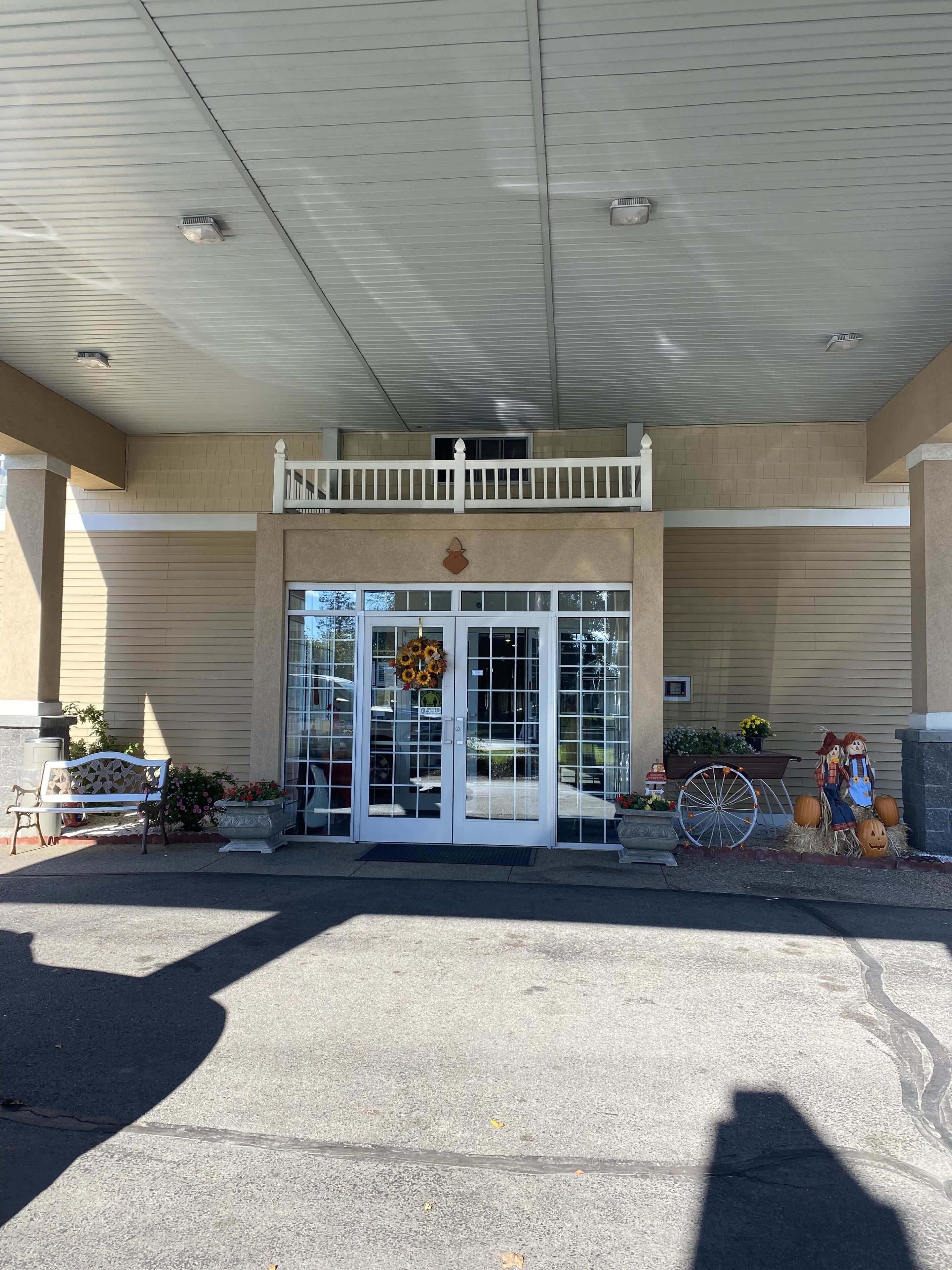 A building entrance with a covered porch, a bench, and a decorative wreath.