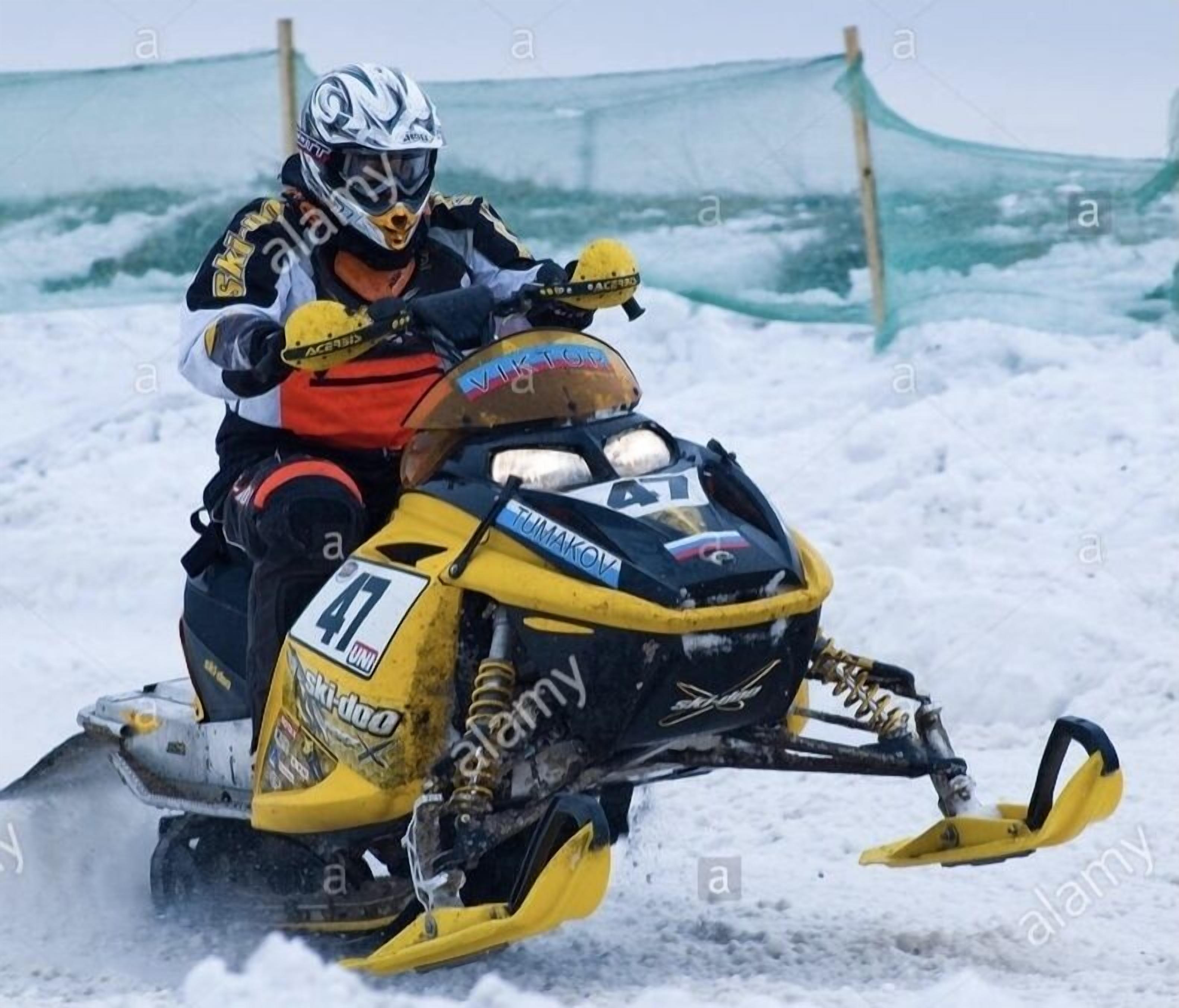 Un vehículo de nieve con un conductor, un casco y el número 47 en la parte delantera.