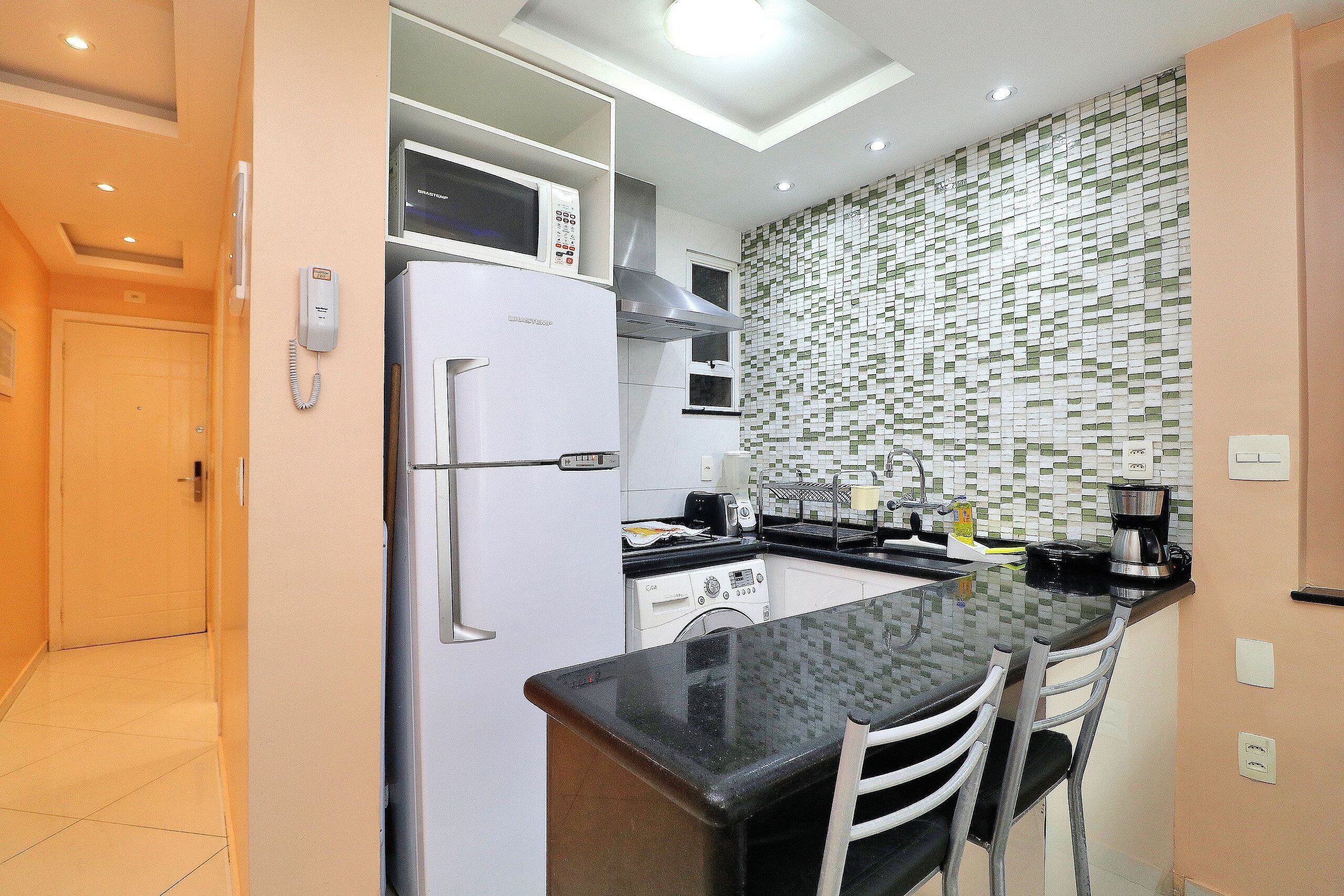 A compact kitchen with a refrigerator, microwave, and a coffee maker on the counter.