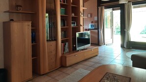 A living room with wooden furniture, a television, and a window with curtains. - Bungalow in Waldbrunn (Waldbrunn)