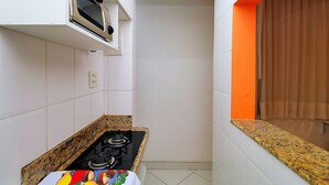 Una cocina con armarios blancos, estufa a gas y microondas.