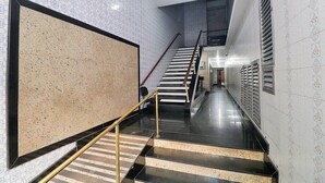 Un pasillo moderno de hotel con una pared de mármol pulido, una escalera con barandilla y azulejos decorativos en las paredes.