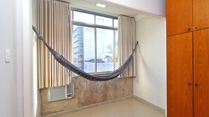 A room with a hammock, a window with curtains, a wooden wardrobe, and a radiator. - Rio Spot U041 (Rio de Janeiro)