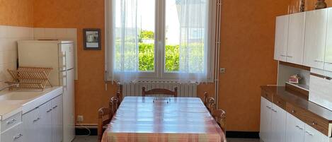 Une cuisine de taille réduite avec une table à manger, des meubles blancs et une fenêtre avec des rideaux.