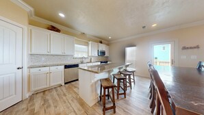 A kitchen with white cabinets, a granite countertop, a built-in microwave, and a wooden island with bar stools. - Bellagio: 5  BR, 3.5  BA House in Crystal Beach, Sleeps 18 (Bolivar Peninsula)