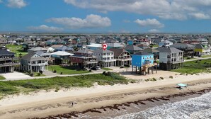A coastal residential area with beachfront properties, including houses with elevated structures and a beach in the foreground. - Bellagio: 5  BR, 3.5  BA House in Crystal Beach, Sleeps 18 (Bolivar Peninsula)