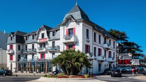 A multi-story hotel with balconies, a central courtyard with palm trees, and a clear blue sky. - Apartment in La Baule by the Beach (Pornichet)