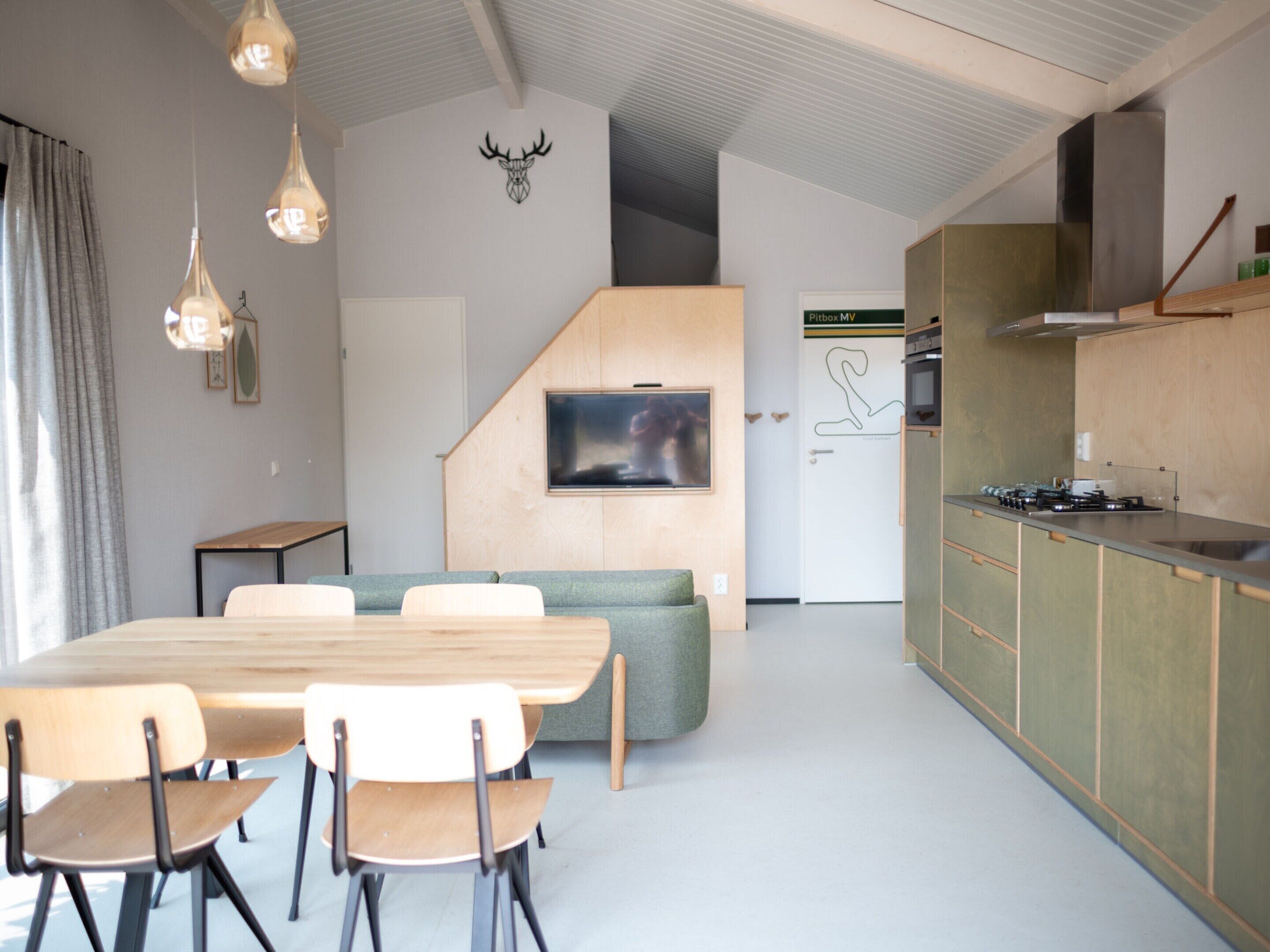 A modern kitchen with a built-in stove, wooden cabinets, and a dining area with a table and chairs.