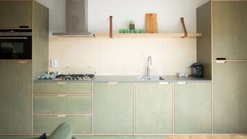 Une cuisine moderne équipée d’une cuisinière à gaz, d’un évier et de meubles de rangement en bois.