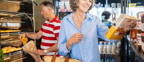 A buffet area with a man in a striped shirt serving food and a woman in a blue shirt holding a box of cereal.