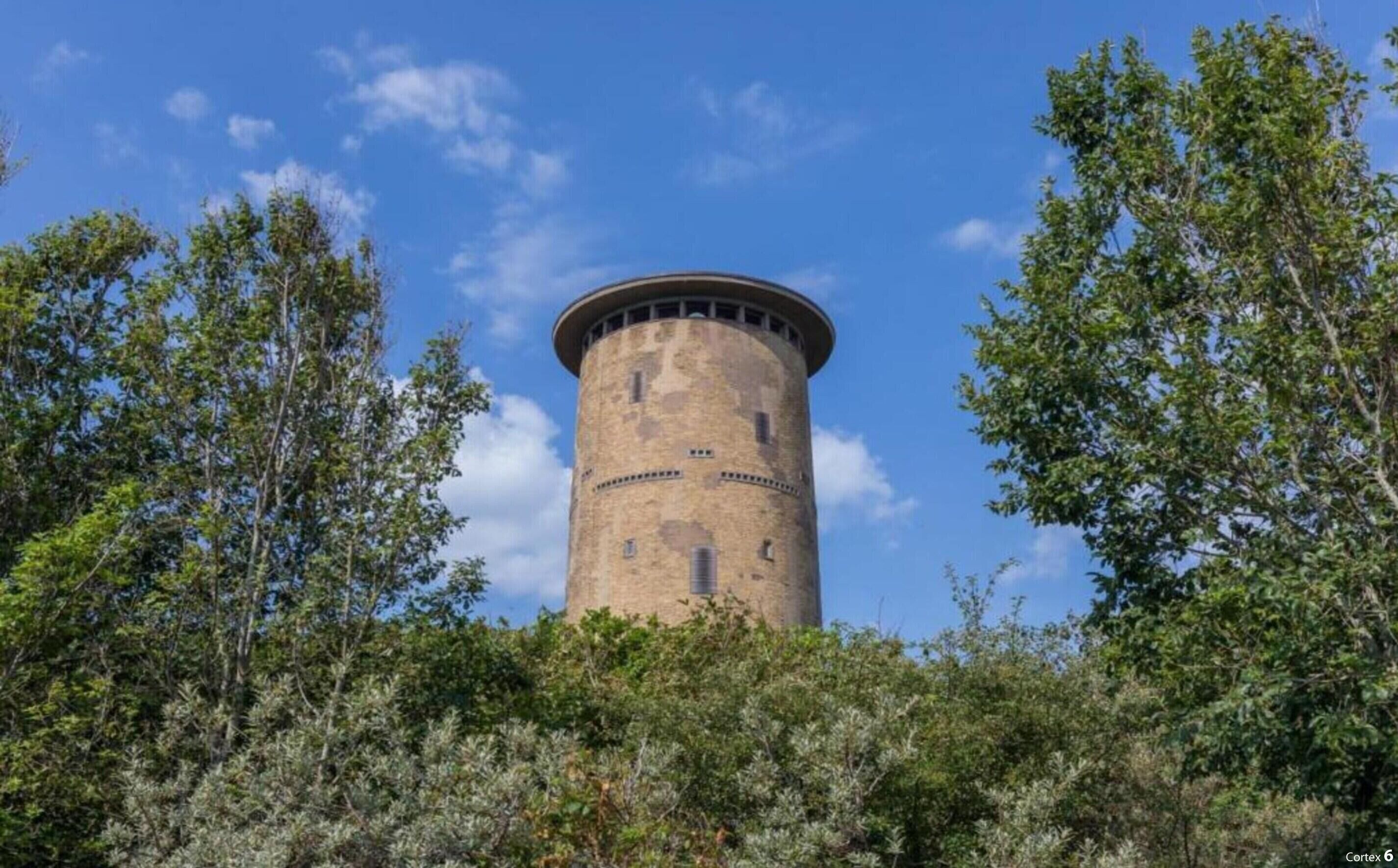 A cylindrical tower with a flat top, surrounded by dense foliage.