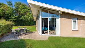 Ein modernes Haus mit Glastür und Terrassenzugang mit Gartenmöbeln.