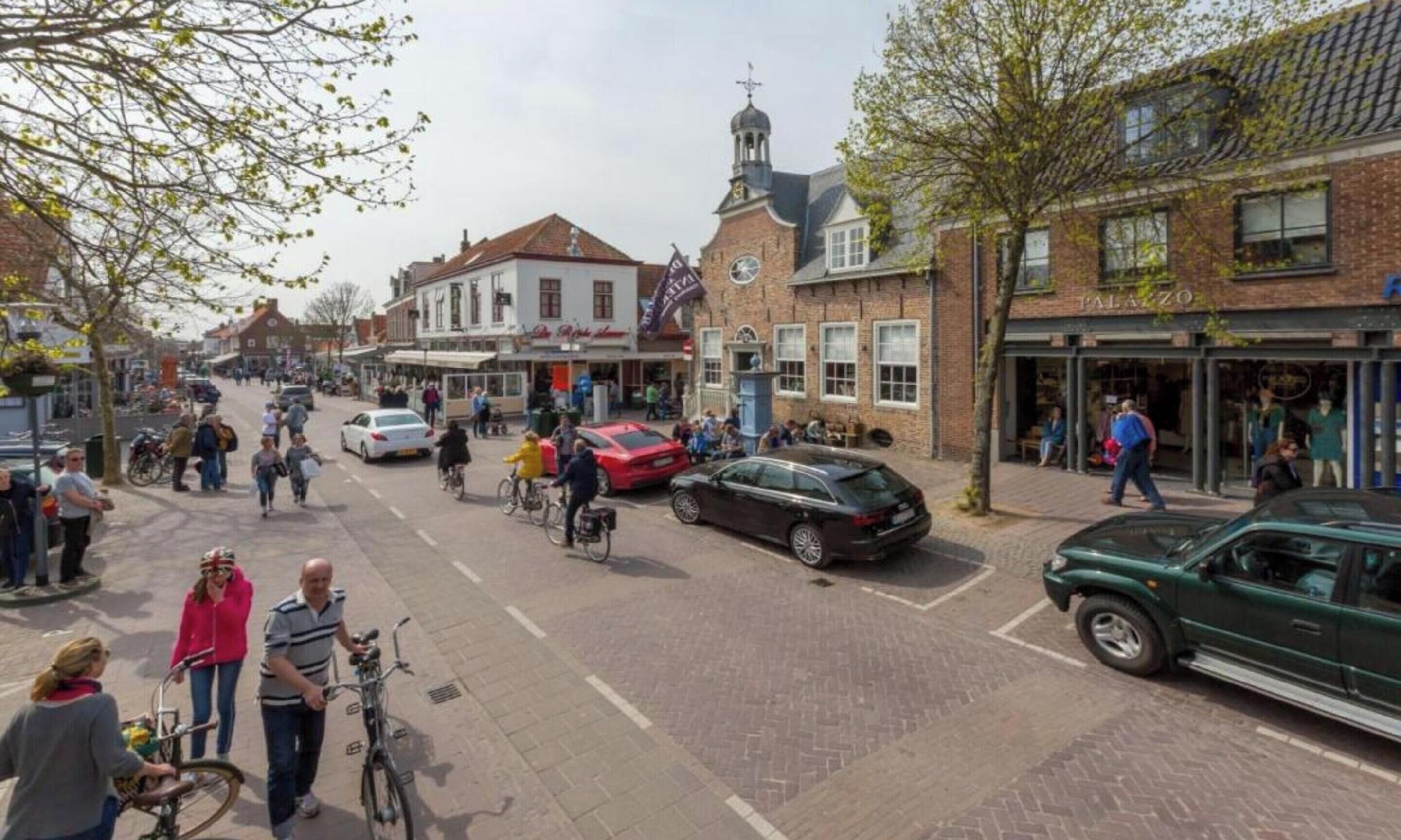 A street scene with pedestrians, bicycles, and cars.