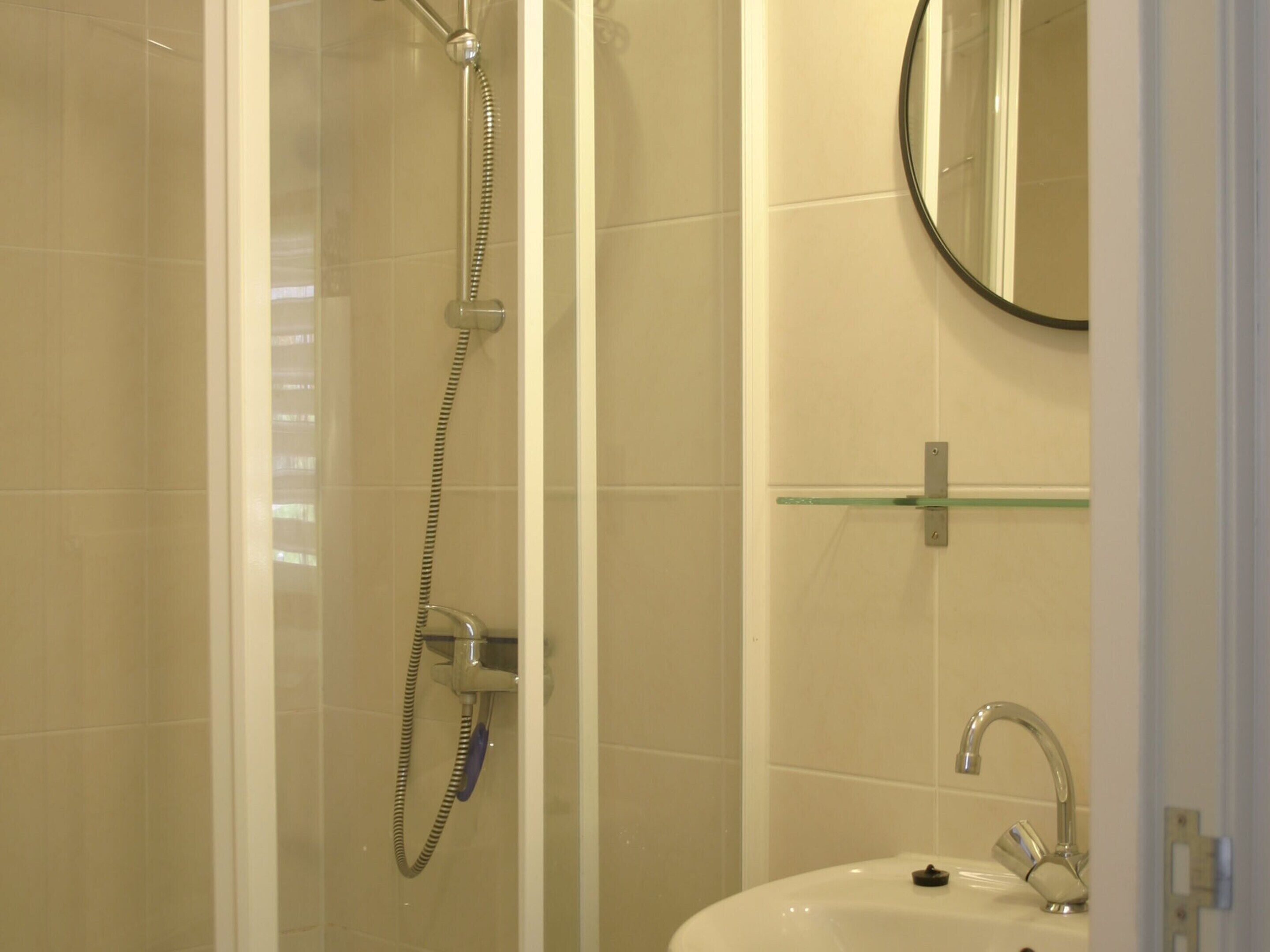 A bathroom with a glass-enclosed shower, a sink with a modern faucet, and a mirror above the sink.