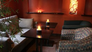 Un rincón acogedor con un sofá, un sillón estampado y una mesa con velas.