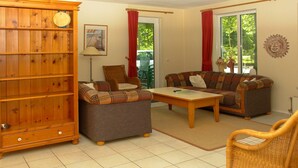 A living room with a sofa, armchair, coffee table, and a wooden cabinet.