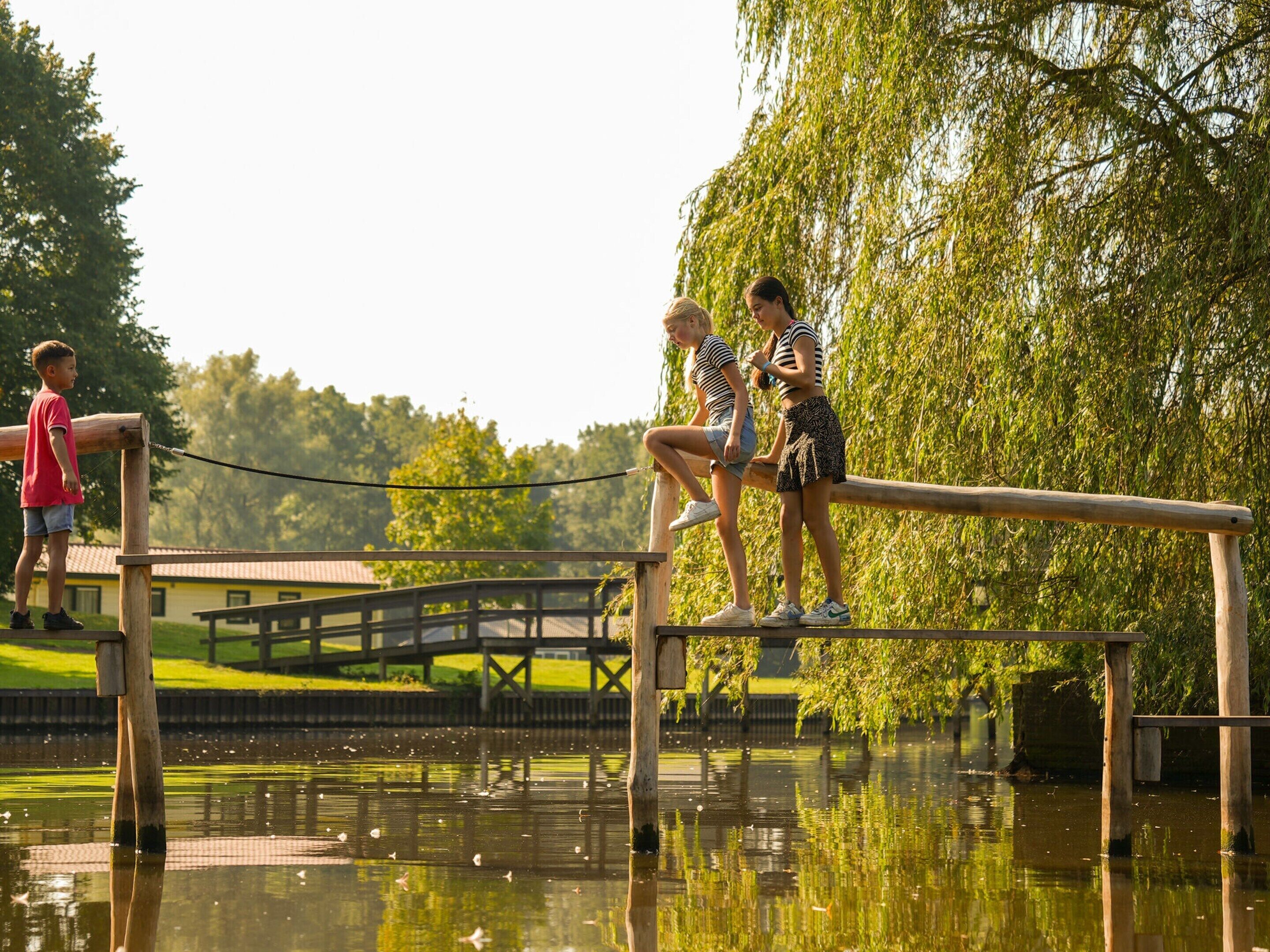 A wooden bridge over a body of water with a wooden deck and railings.