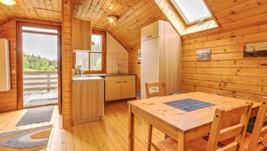A cozy wooden cabin with a kitchen, dining area, and a large window overlooking a forest. - Holiday Home in Liebenfels in Carinthia (Liebenfels)