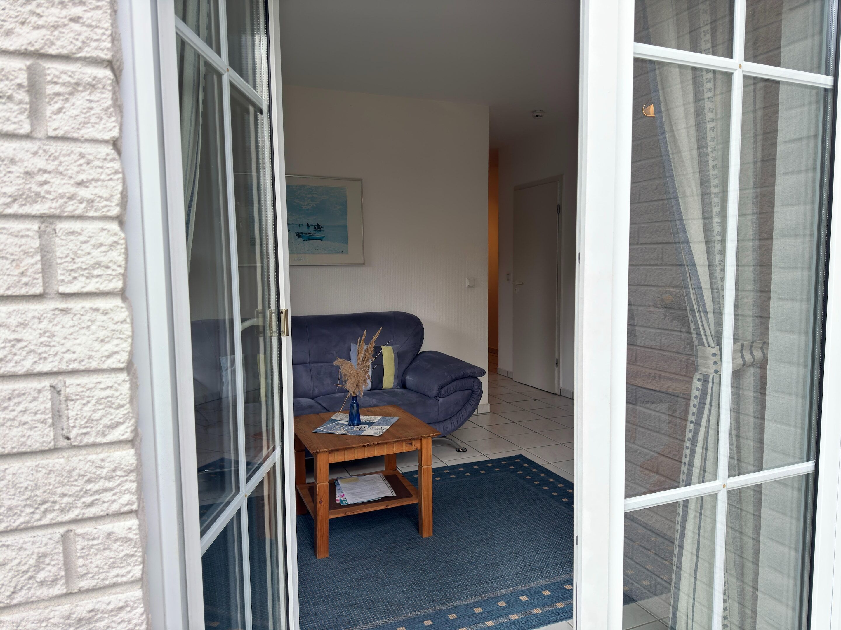 Een woonkamer met een bank, een bijzettafeltje en een blauw vloerkleed.