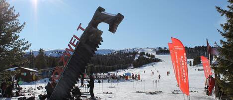 A ski resort with a large metal sculpture, ski equipment, and flags.