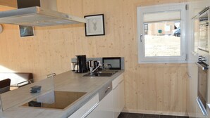 Eine moderne Küche mit einer zentralen Kochinsel, Edelstahlgeräten und Blick ins Freie durch ein Fenster.