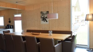 Ein moderner Essbereich mit Holztisch und Stühlen, einer Pendelleuchte und Blick ins Freie.