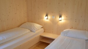 Ein Zimmer mit zwei Einzelbetten, Holzwänden und zwei Wandleuchten.