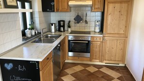 A kitchen with wooden cabinets, a Bosch oven, a sink, and a coffee maker. - Schones Ferienhaus in Dargun mit Pool (Dargun)