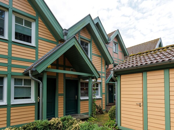 A traditional building with a green and beige facade, multiple windows, and a visible door. - Cozy Holiday Home with Wood Burning Stove near Water (Rheinsberg)