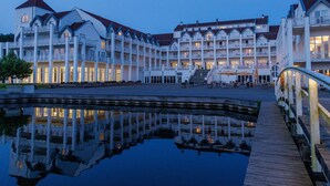A waterfront hotel with multiple balconies and a reflection pool. - Cozy Holiday Home with Wood Burning Stove near Water (Rheinsberg)