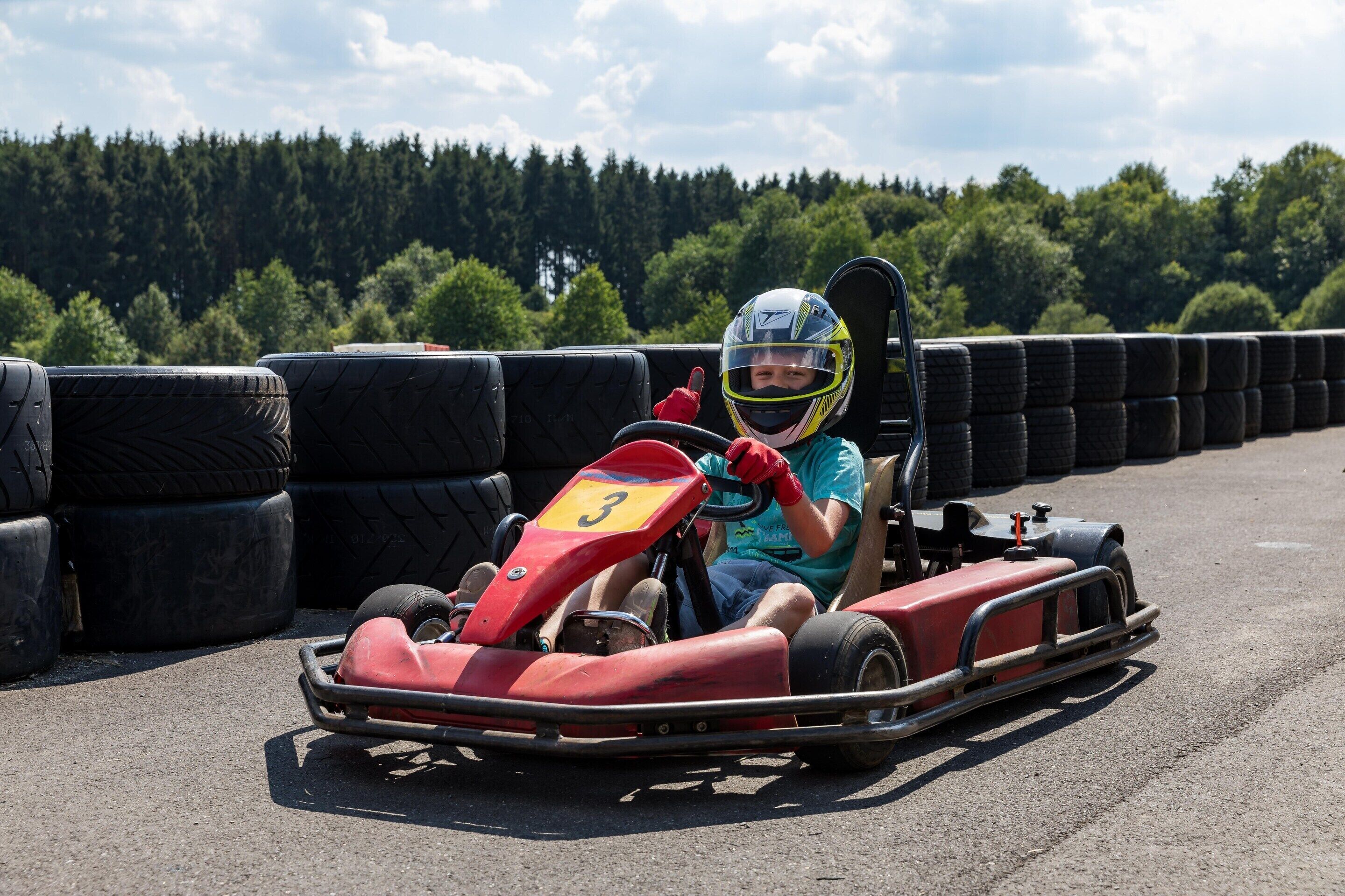 Eine Go-Kart-Bahn, auf der ein Kind ein rotes Go-Kart fährt.