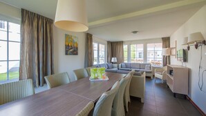 A spacious living area with a large dining table, comfortable seating, and large windows offering views of the outdoors. - Relaxing Countryside Villa (Bad Bentheim)