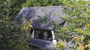 A house with a sloped roof, surrounded by dense foliage. - Chalet in Gerolstein Forest Holiday Park (Gerolstein)