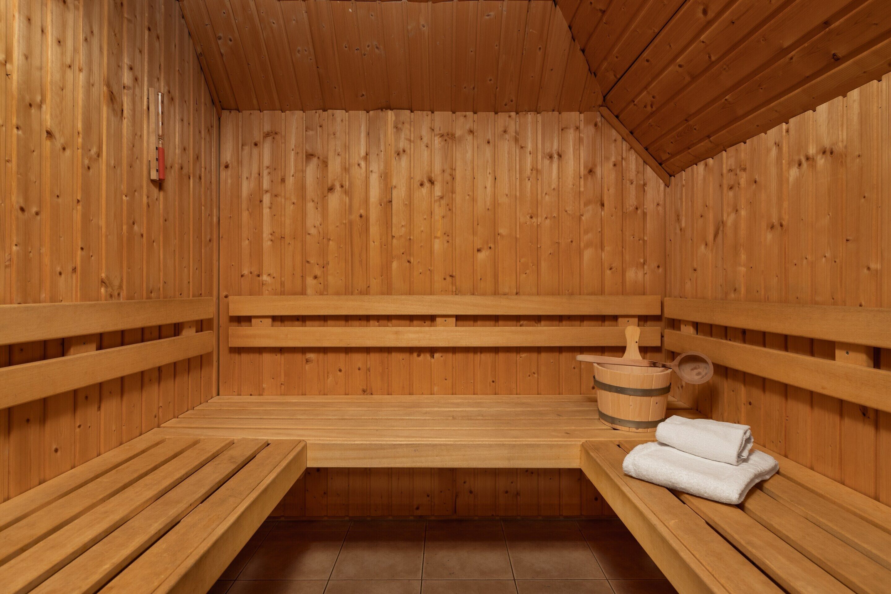 A sauna with wooden benches, a wooden bucket, and a towel.
