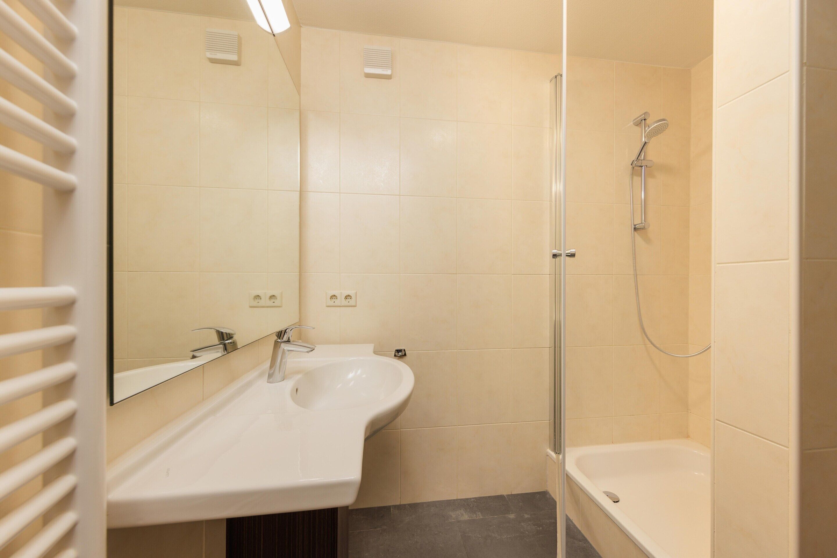Un baño con lavamanos, espejo, ducha y bañera.