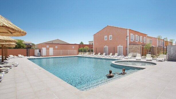Ein Pool mit Liegestühlen und ein Gebäude mit roter Fassade.