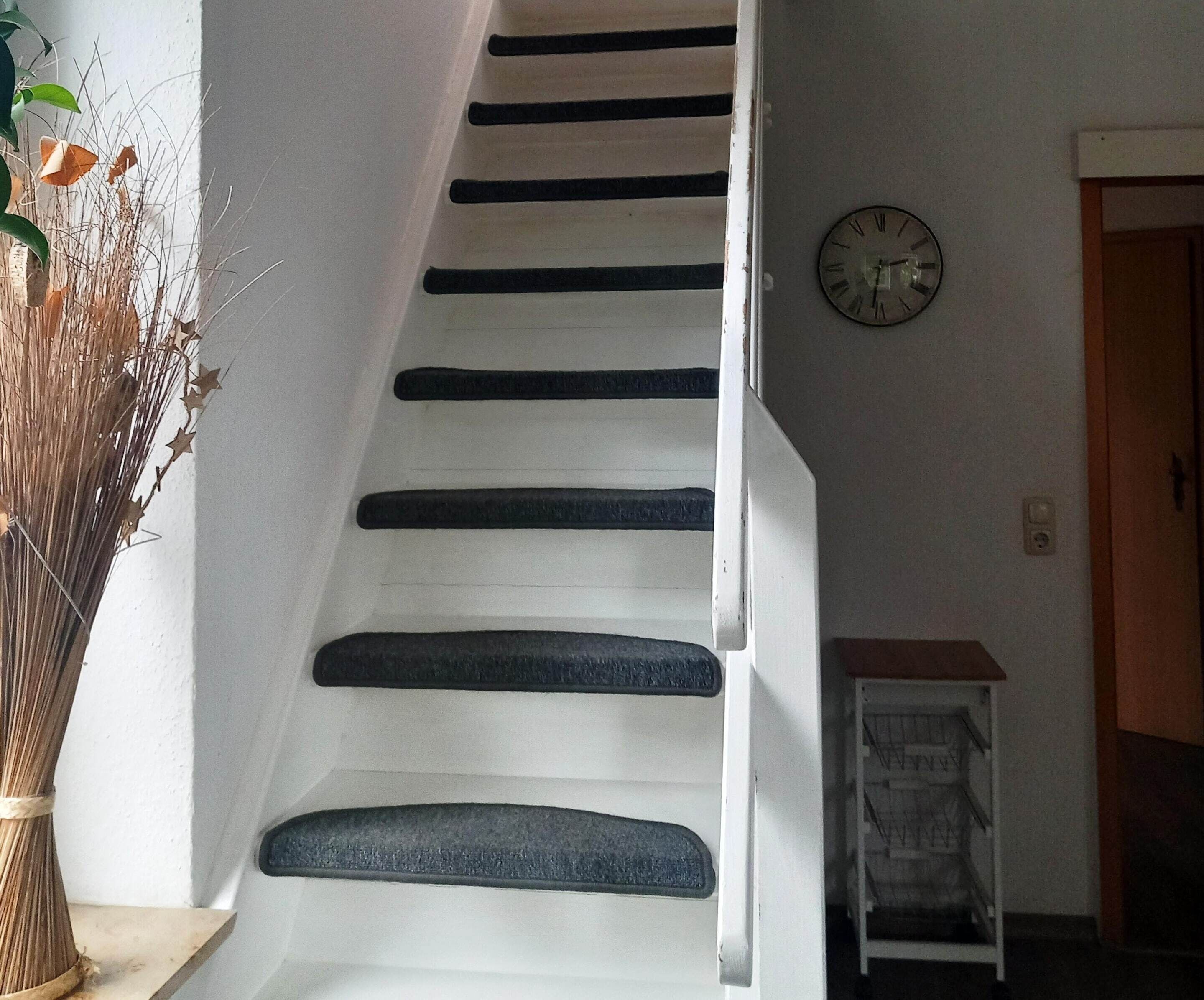 A staircase with dark steps and a wall clock.