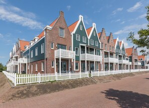 A row of traditional Dutch houses with red-tiled roofs and white railings, featuring balconies and brick facades. - Holiday Home in Volendam Near Marina (Volendam)