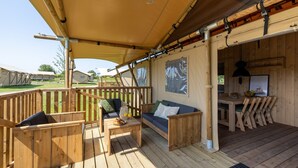 A wooden deck with a sofa, table, and chairs, a dining area, and a covered section with a hanging light fixture. - Detached Holiday Home With Garden Near Hoorn (Andijk)