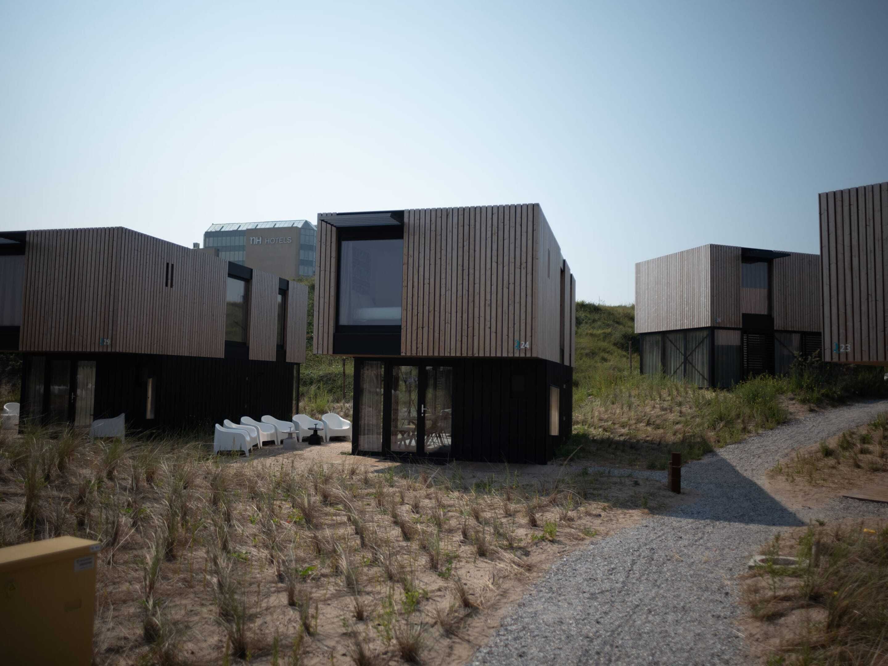 A modern hotel with modular, wooden cabins featuring large windows and a gravel path leading to the entrance.