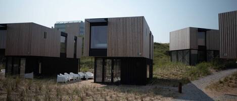 Un hotel modern amb cabines de fusta modulars, grans finestres i un camí de grava que condueix a l'entrada.