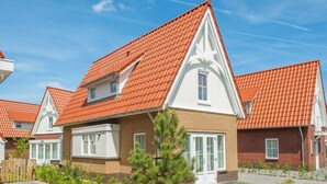 Ein Wohngebäude mit rotem Ziegeldach, weißer Fassade und Backsteinaußenwand.