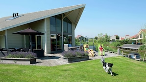 A modern house with a patio, outdoor furniture, and a dog.